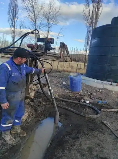 Máquina perforadora de HidroNQN trabajando entre filas de árboles frutales en una chacra de Neuquén.